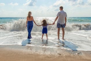 Family of three standing on a beach