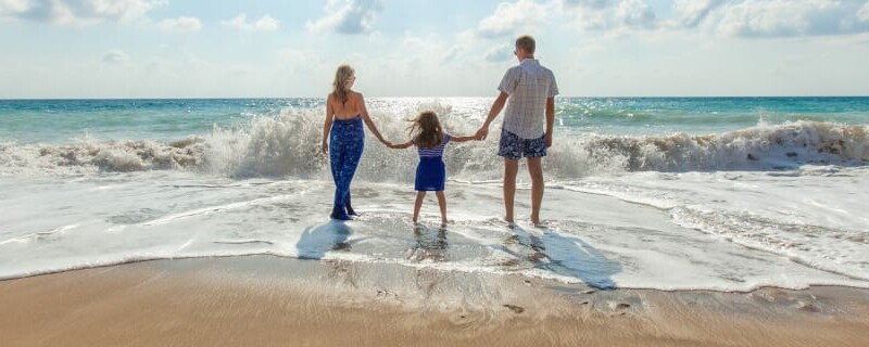 Family of three standing on a beach