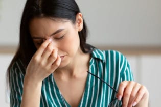 woman having eyes fatigue massaging nosebridge work