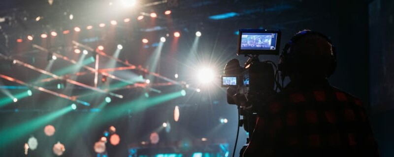 Man filming a live music performance, with green and red lighting